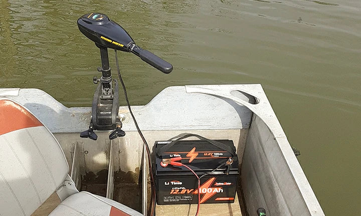 A LiTime 100Ah battery sitting on the floor of a boat, powering the transom-mounted trolling motor