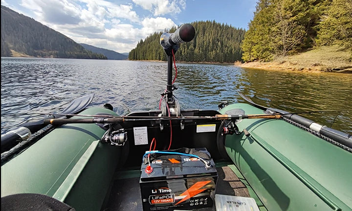 A LiTime battery neatly installed at the bow of an inflatable boat on a scenic mountain lake