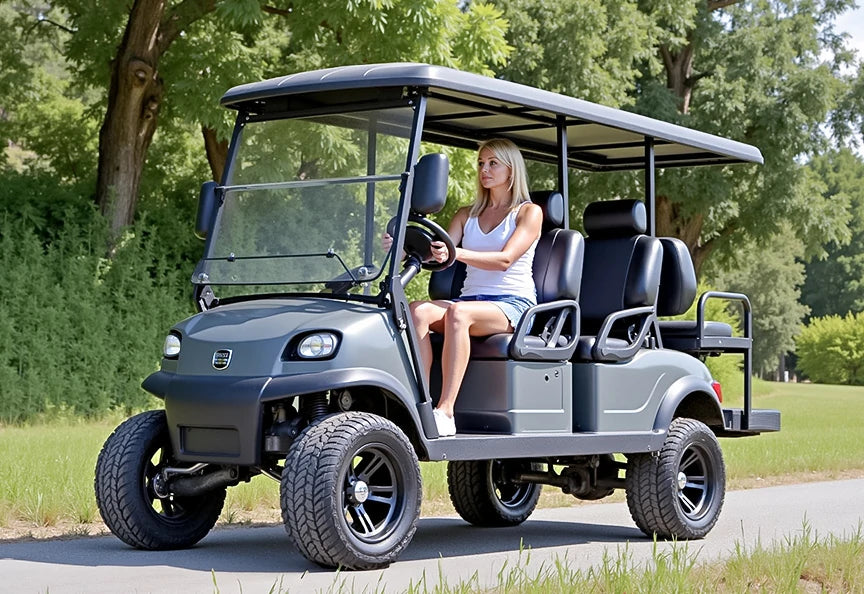 A woman driving a gray golf cart on a path surrounded by greenery, showcasing golf cart lithium batteries.