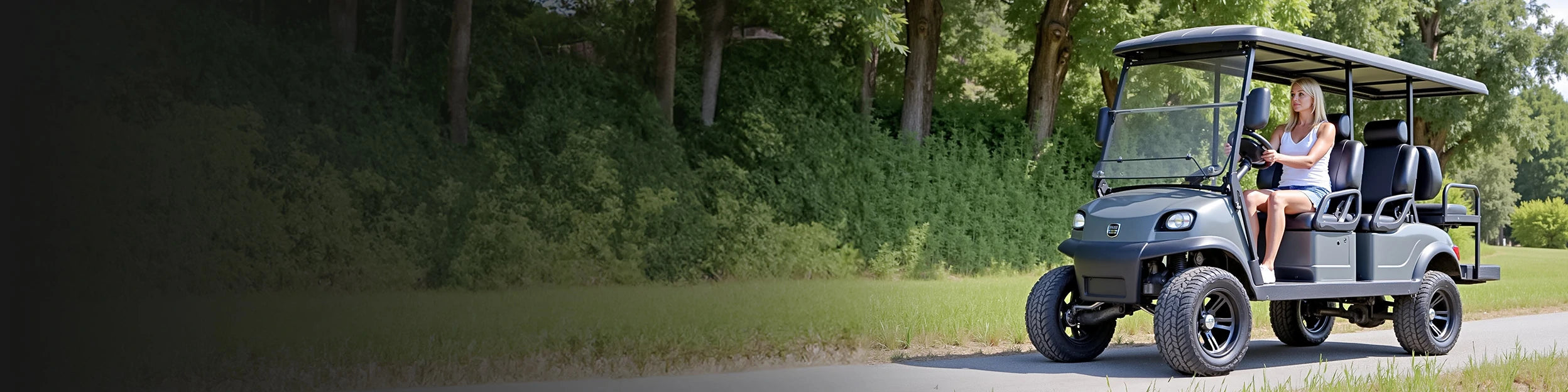 A woman driving a gray golf cart on a path surrounded by greenery, showcasing golf cart lithium batteries.