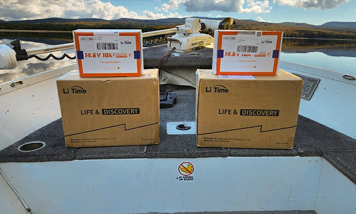 Two boxed LiTime batteries and chargers await installation on the deck of a boat, ready for adventure