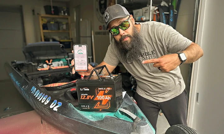 a man by his boat with a 12V 100Ah group 24 battery and smartphone, showing bluetooth function