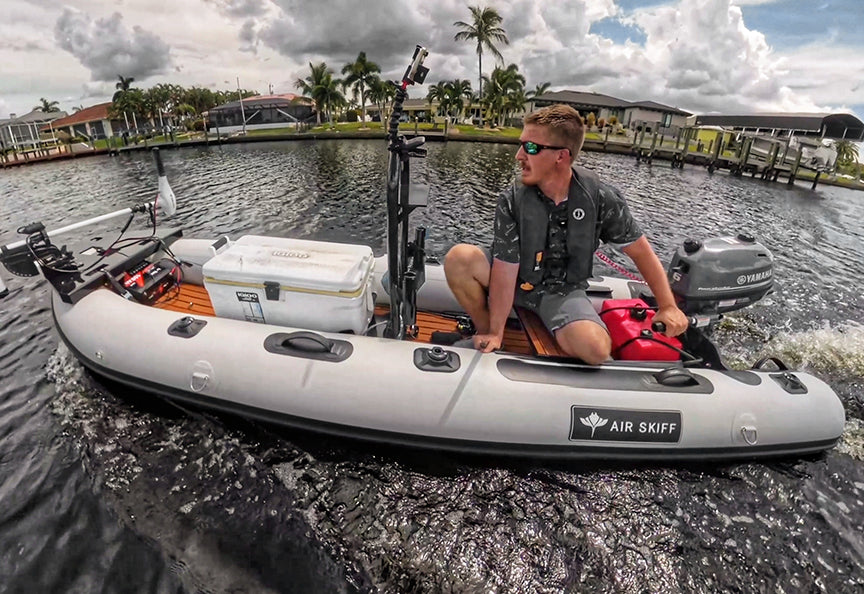 A young man pilots an inflatable sport canoe with a trolling motor through a calm, tropical waterway